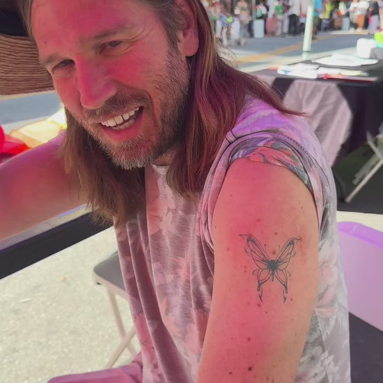Close-up video of a realistic butterfly temporary tattoo applied on a man’s arm and a woman’s forearm using water-free temporary tattoo technology