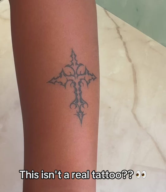 Close-up of an artist-designed temporary cross tattoo showing realistic skin movement, natural blue-black ink color, and a real tattoo look.