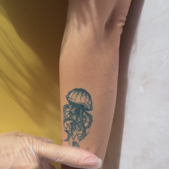 Realistic jellyfish temporary tattoo on calf with detailed flowing tentacles and natural blue-black color. Close-up video showcases the skin-like finish and realistic tattoo appearance of Alter Ego Ink’s water-free tattoo technology.