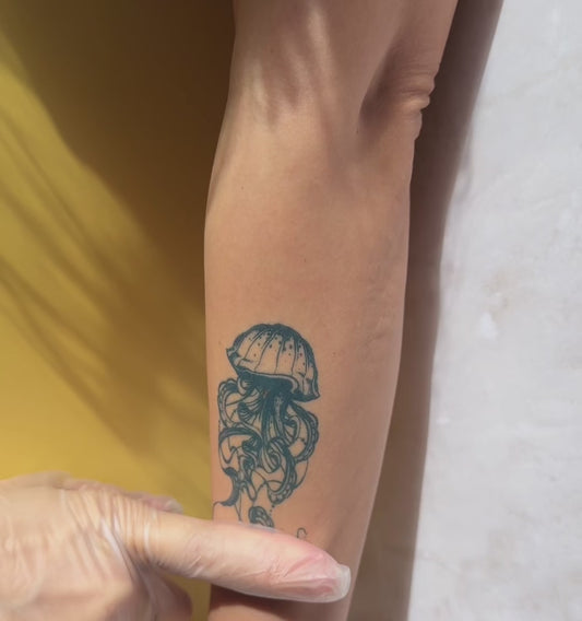 Realistic jellyfish temporary tattoo on calf with detailed flowing tentacles and natural blue-black color. Close-up video showcases the skin-like finish and realistic tattoo appearance of Alter Ego Ink’s water-free tattoo technology.