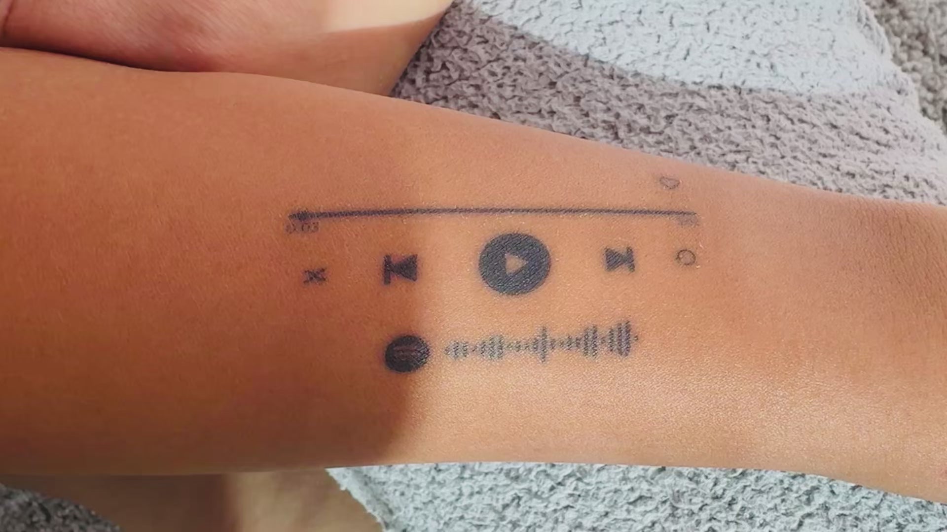 Close-up video of the On Repeat music player temporary tattoo on skin